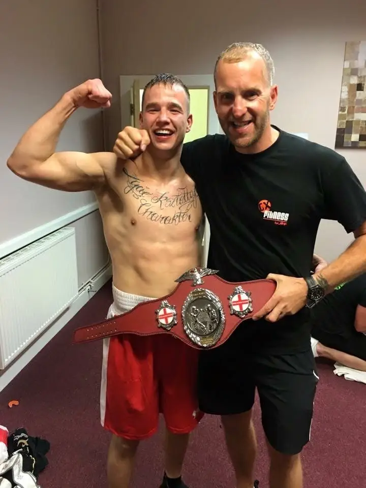 Fighter holding a championship belt with his coach, The Bar Gym fight school Worthing
