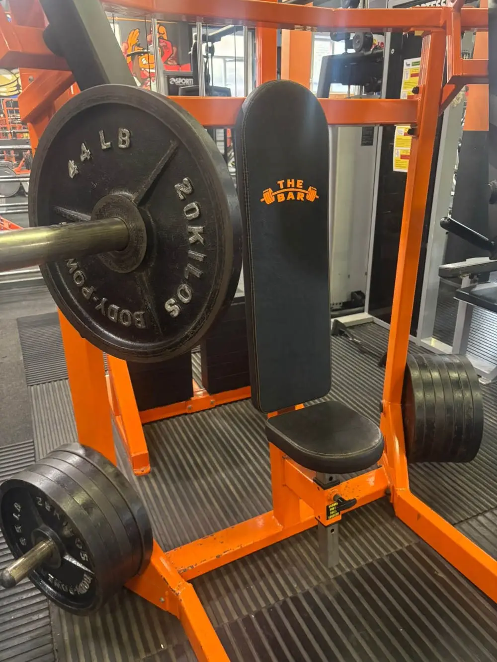Orange plate-loaded press machine with The Bar branding at The Bar Gym Worthing
