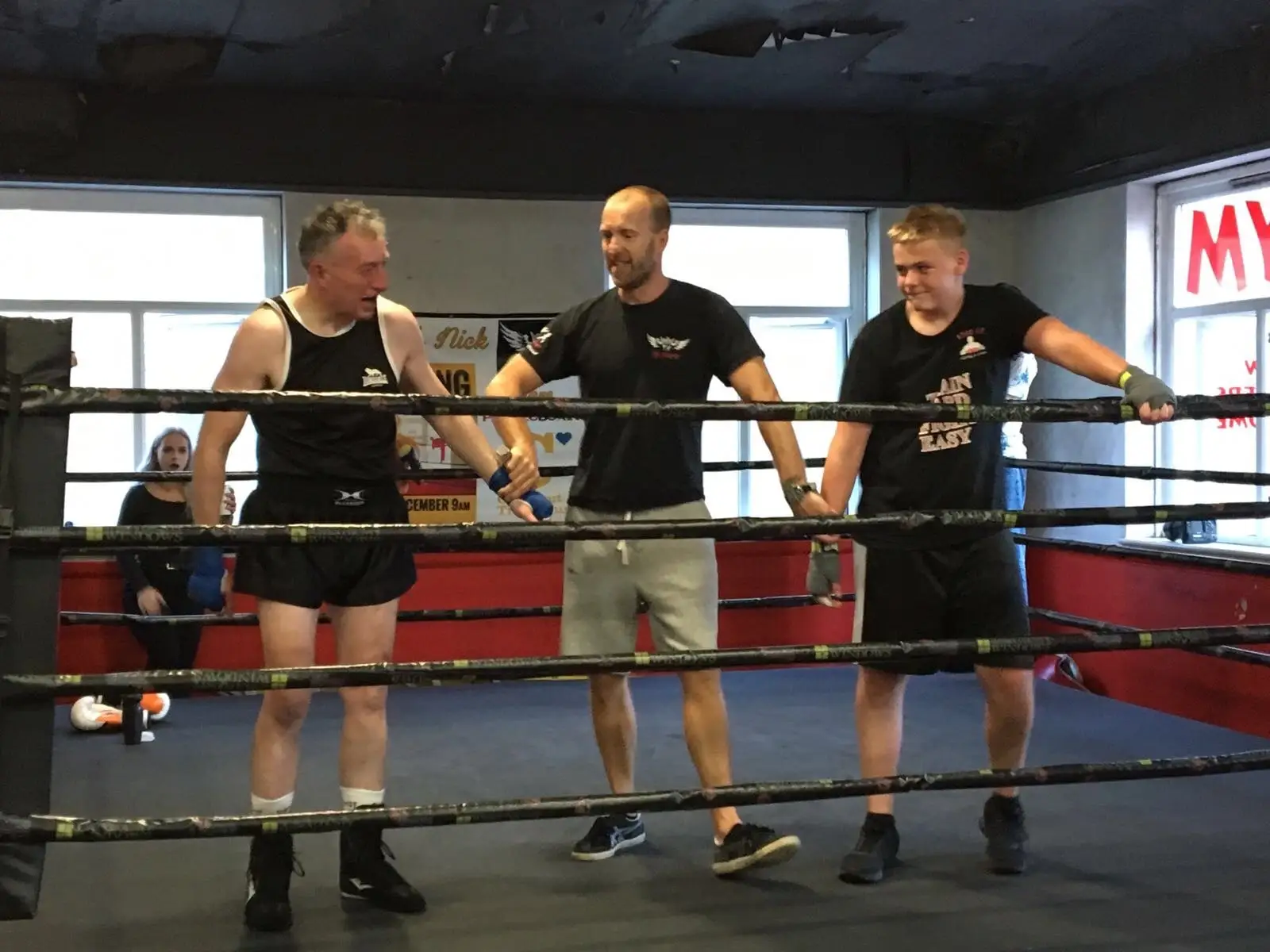 Coaches and a fighter standing in the boxing ring at The Bar Gym Worthing