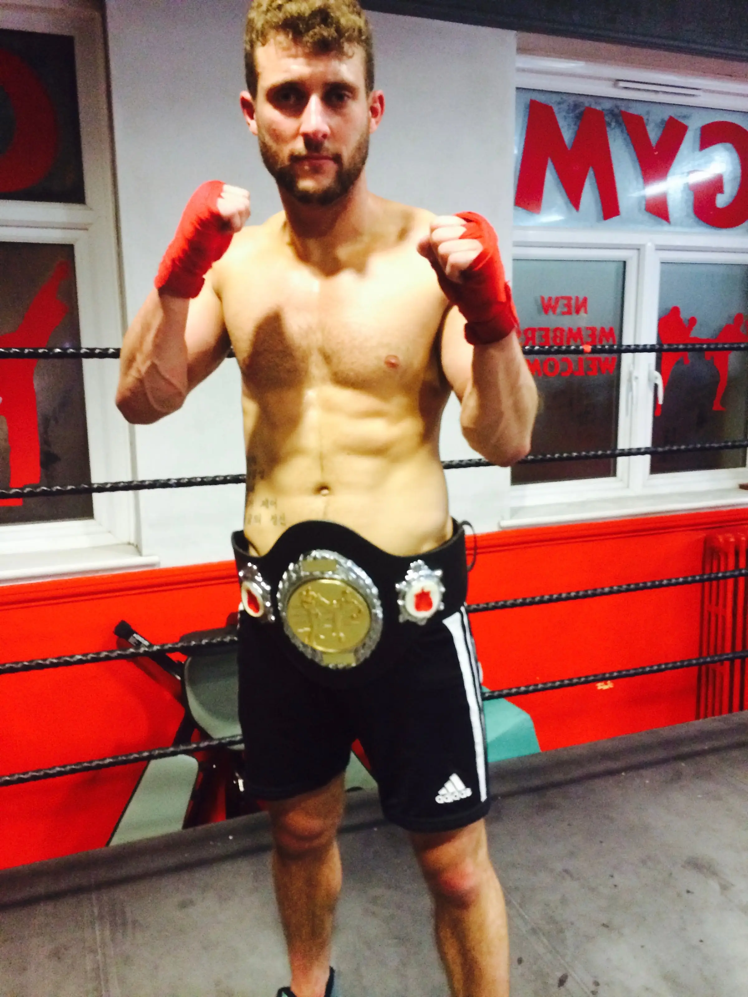 Fighter wearing a title belt and gloves, The Bar Gym fight school Worthing